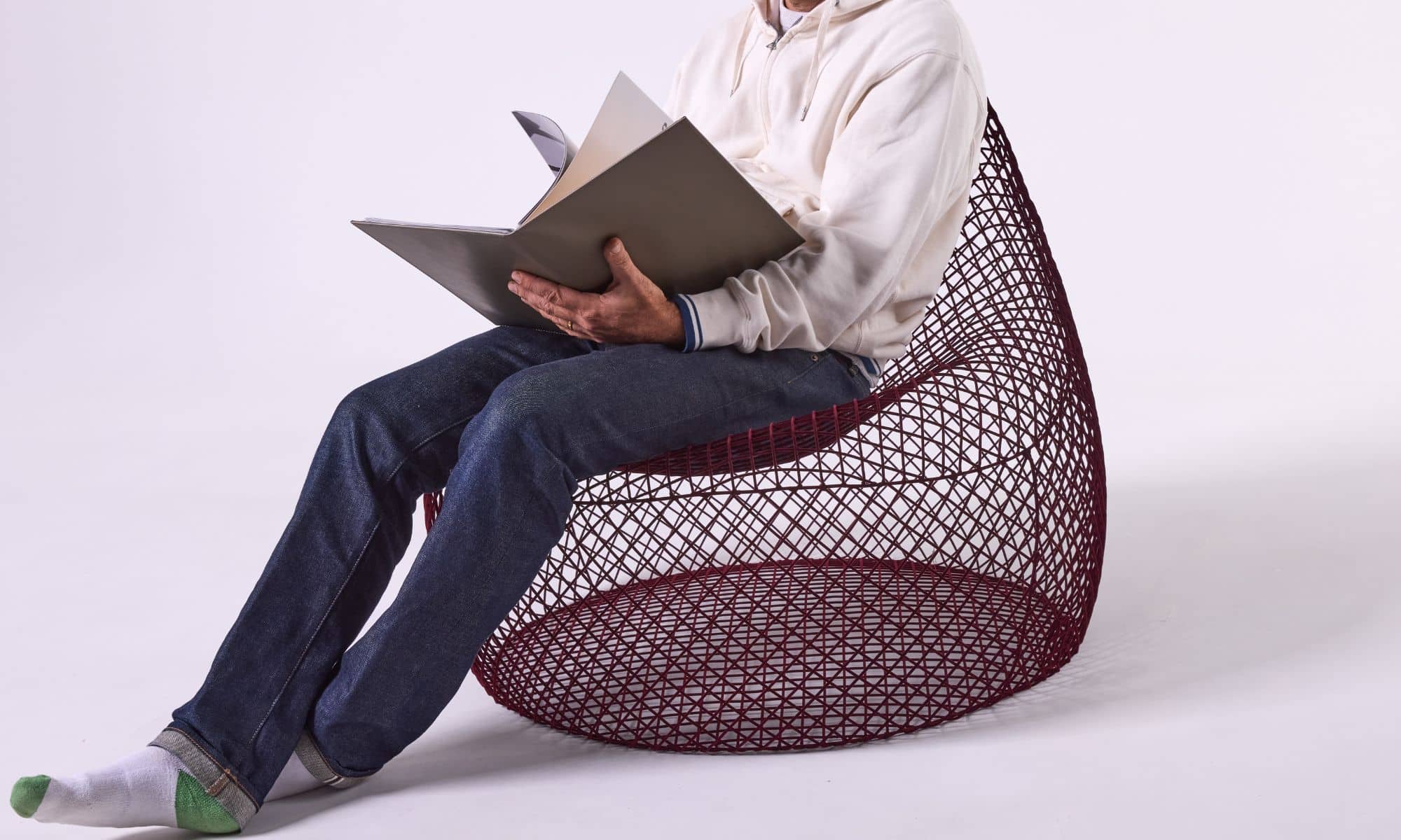 A man sitting in a burgandy wire bean bag reading a book